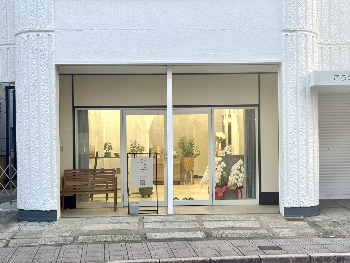 鴻巣市のまつげエクステ専門サロン「アイデザイン ツツ.」の店舗外観 - 白い外壁とガラス張りの明るい入口、鴻巣駅東口から徒歩5分の好立地